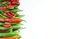Pile of hot peppers border with space for text. Different green and red hot chili peppers frame isolated on white Royalty Free Stock Photo