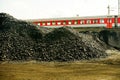 Pile of industrial coal and a train. Fuel and power generation, nature pollution theme. Royalty Free Stock Photo