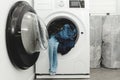 Pile of jeans in the drum of open washing machine in laundry room.