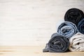 Pile of jeans on light wooden background, space for text