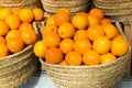 Pile of juicy oranges in wicker baskets on market counter Royalty Free Stock Photo