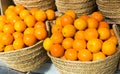 Pile of juicy oranges in wicker baskets on market counter Royalty Free Stock Photo