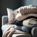 Pile of knitted warm sweaters on sofa in living room