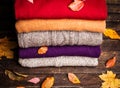 Pile of knitted winter clothes on wooden background covered with