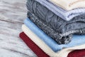 Pile of knitted winter clothes and wool sweaters on wooden background. Royalty Free Stock Photo