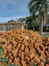 Pile of loose red bricks stacked on ground at construction site.