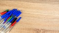 Pile of a lot multi colored plastic ballpoint pens on wooden table. Abstract stationery background. Top view, flat lay. Copy space