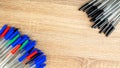 Pile of a lot multi colored plastic ballpoint pens on wooden table. Abstract stationery background. Top view, flat lay. Copy space