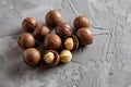 Pile macadamia nuts open kernels and shells on gray concrete background, top view