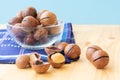 Pile of macadamia nuts in whole kernels and half opened on wooden background with darl blue napkin and translucent bowl. Seeds of Royalty Free Stock Photo
