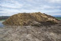 Pile of manure in the countryside with blue sky. Heap of dung in field on the farm yard with village in background