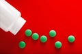 Pile of medical pills in green and white jar on clean red background. Layout for the designer.