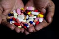 Pile of medicine pills tablets capsules in a both hands in black background Royalty Free Stock Photo