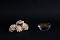 A pile of meringues and a bowl of cinnamon powder on black background