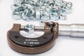 Pile of metal nuts and analog micrometer Royalty Free Stock Photo