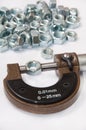 Pile of metal nuts and analog micrometer Royalty Free Stock Photo