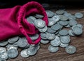 Pile of money coins from red cloth bag on rustic old wooden table. Concept for growth business and saving money