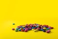 Pile of multi colored chocolate candies with copy space on yellow background Royalty Free Stock Photo