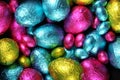 Pile of multi coloured and different sizes of colourful foil wrapped chocolate easter eggs in pink, blue, yellow and lime Royalty Free Stock Photo