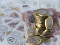 Stack of new pound sterling coins on semi circle of ten pound notes