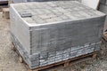 Pile of new grey paving stones on wooden pallet fixed with stretch wrap. Building material for the pavement reconstruction.