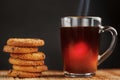 A pile of oatmeal cookies with chocolate chips and a mug of fragrant black hot tea in on a bamboo substrate, on a dark background Royalty Free Stock Photo