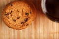 A pile of oatmeal cookies with chocolate chips and a mug of fragrant black hot tea in on a bamboo substrate, on a dark background Royalty Free Stock Photo