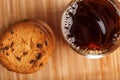 A pile of oatmeal cookies with chocolate chips and a mug of fragrant black hot tea in on a bamboo substrate, on a dark background Royalty Free Stock Photo