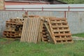 A pile of old brown wooden pallets outdoors in green grass