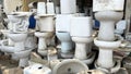 Pile of old and dirty damaged ceramic toilets at a used toilet dealer