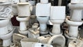 Pile of old and dirty damaged ceramic toilets at a used toilet dealer