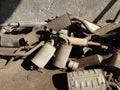 A pile of old rusted car exhausts, silencers, or tail pipes in the backyard of an auto repair shop. Top view, no people