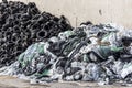 Pile of old used tires and second pile of plastic bags and plastic on the old wall