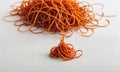 A pile of orange rubber bands sits on a white surface Royalty Free Stock Photo