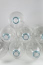 Pile of pack of liter and a half of empty mineral water without caps just with the blue sealing ring on a white