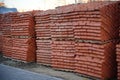 Pile of pallets with red bricks on city street. Building materials on construction site outdoor. Concept of constructing buildings