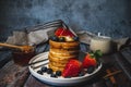 A pile of pancakes with honey, blueberry and strawberry and whip cream on top in plate on wooden table Royalty Free Stock Photo