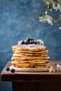 Pile of pancakes topped with edible flowers and blueberries dusted with sugar powder