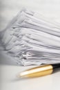 A pile of paper sheets on a white table on a wooden table with a golden pen Royalty Free Stock Photo