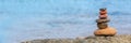 Pile of pebbles on a beach panoramic blue water background