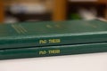 A pile of PhD theses of green cover, office or library background