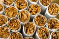 A pile, a pile of cigarettes in front of tobacco, a stack as a background texture, close-up, in front. Royalty Free Stock Photo
