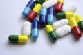 Pile of pills of different colours: blue, yellow, red and white placed on top of white paper. Illustrative for medical, health an Royalty Free Stock Photo