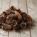 A pile of pine cones (genus Pinus) rests on a wooden surface with a light gray, Royalty Free Stock Photo