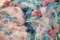 Pile of pink fishing net with blue and green ropes and red buoys on the dock. Royalty Free Stock Photo