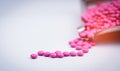 Pile of pink round sugar coated tablets pills on drug tray with copy space.