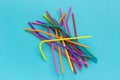 Pile of plastic disposable multi colored drinking straws for cocktails and drinks on blue background. Top view Copy space Royalty Free Stock Photo