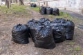 Pile of plastic garbage bags on the roadside near the city building. Garbage bags on the street. Black waste bags Royalty Free Stock Photo