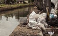 Pile of polythene bags and trash in the streets near a lake. Irresponsible and careless people polluting land and water, messy and