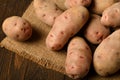 A pile of potatoes on burlap on a dark wood background